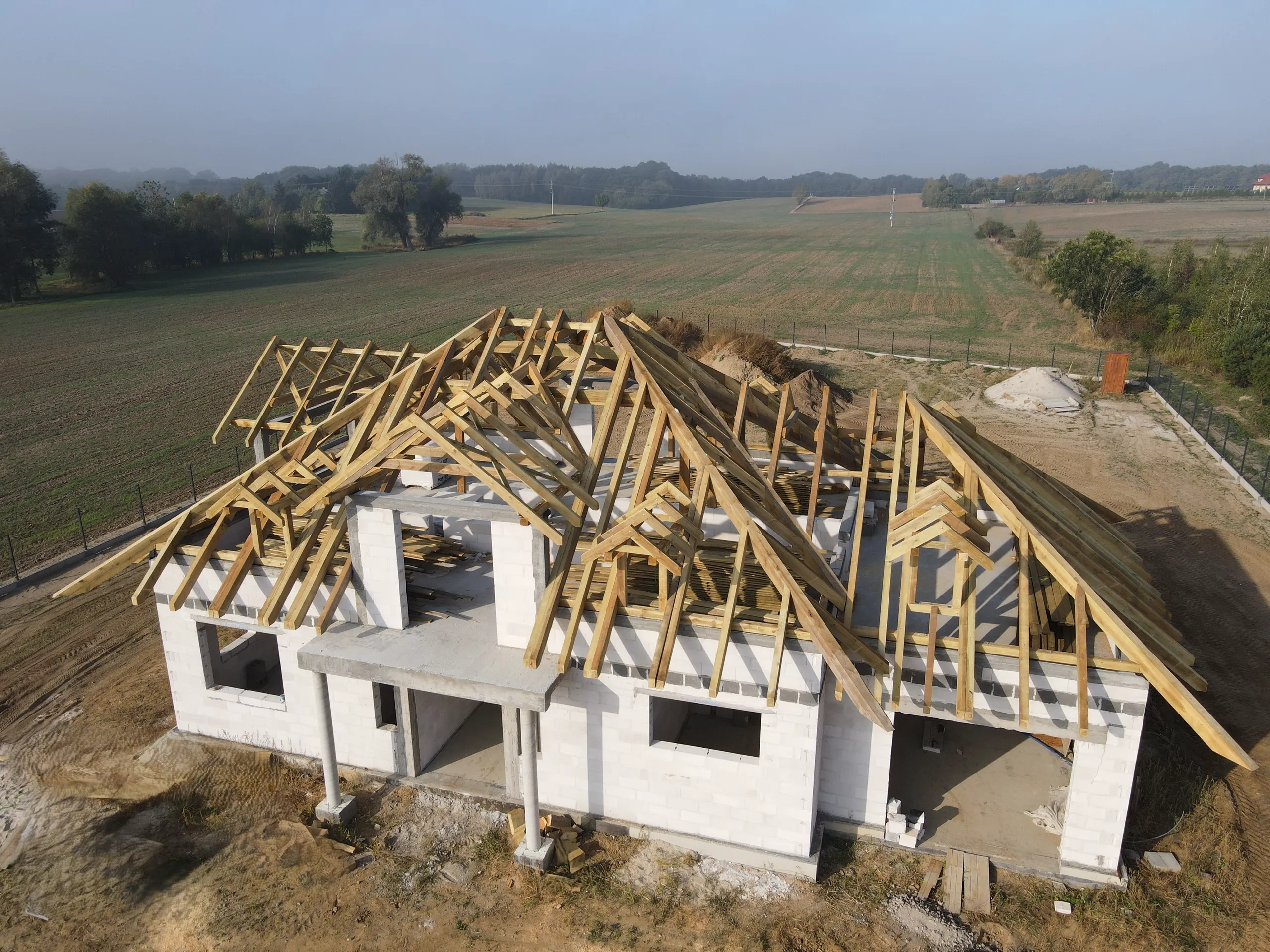 Wiązary dachowe – montaż drewnianych wiązarów dachowych na ścianach budynku w budowie