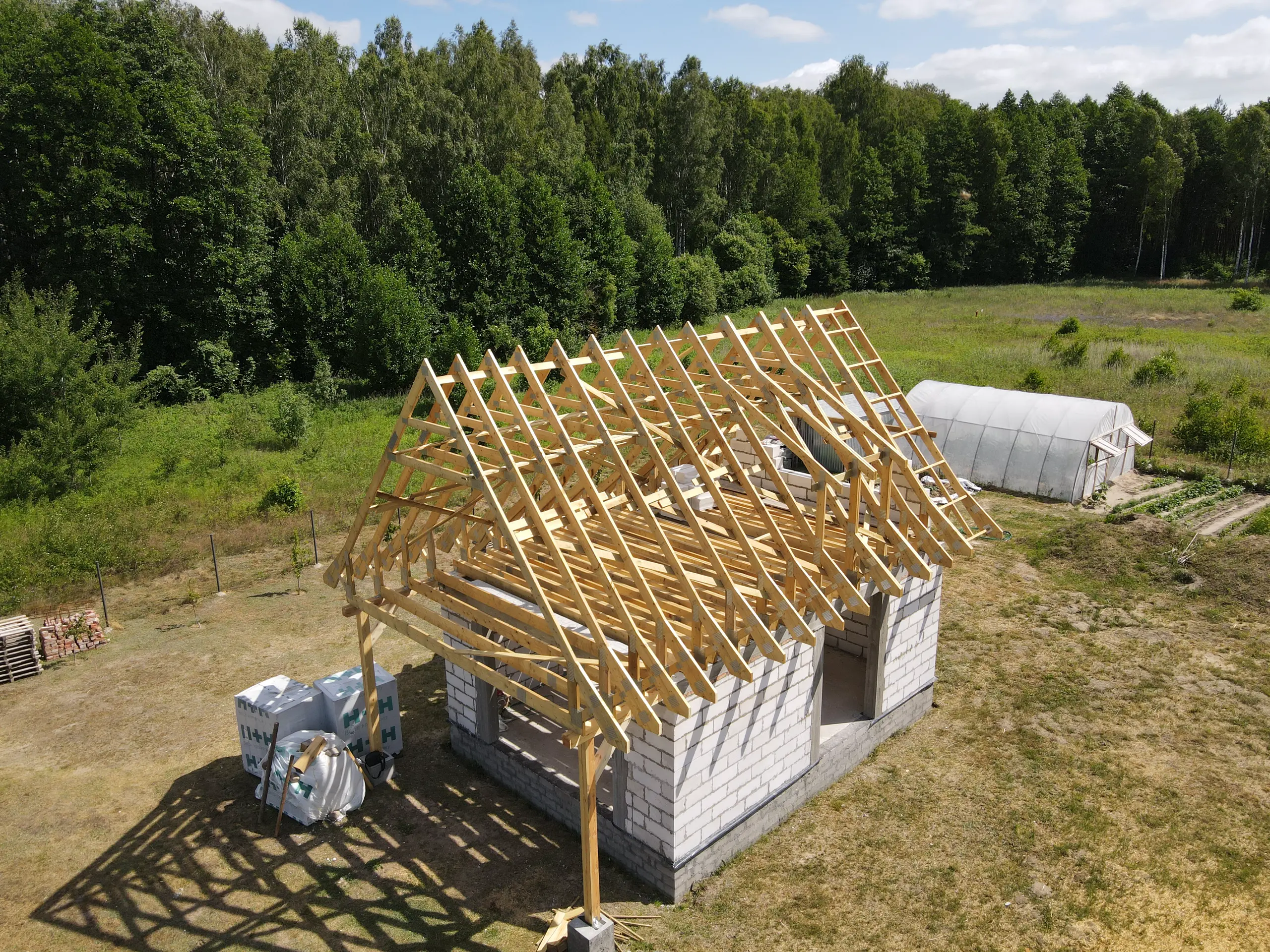 Drewniana więźba prefabrykowana montowana na ścianie murowanego budynku jednorodzinnego
