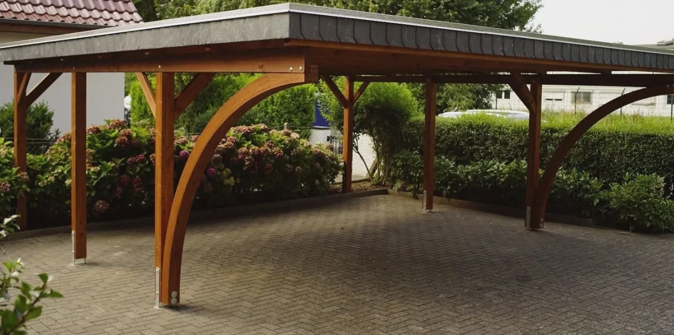Drewniany carport na dwa stanowiska z prefabrykowaną więźbą dachową na podjeździe z kostki